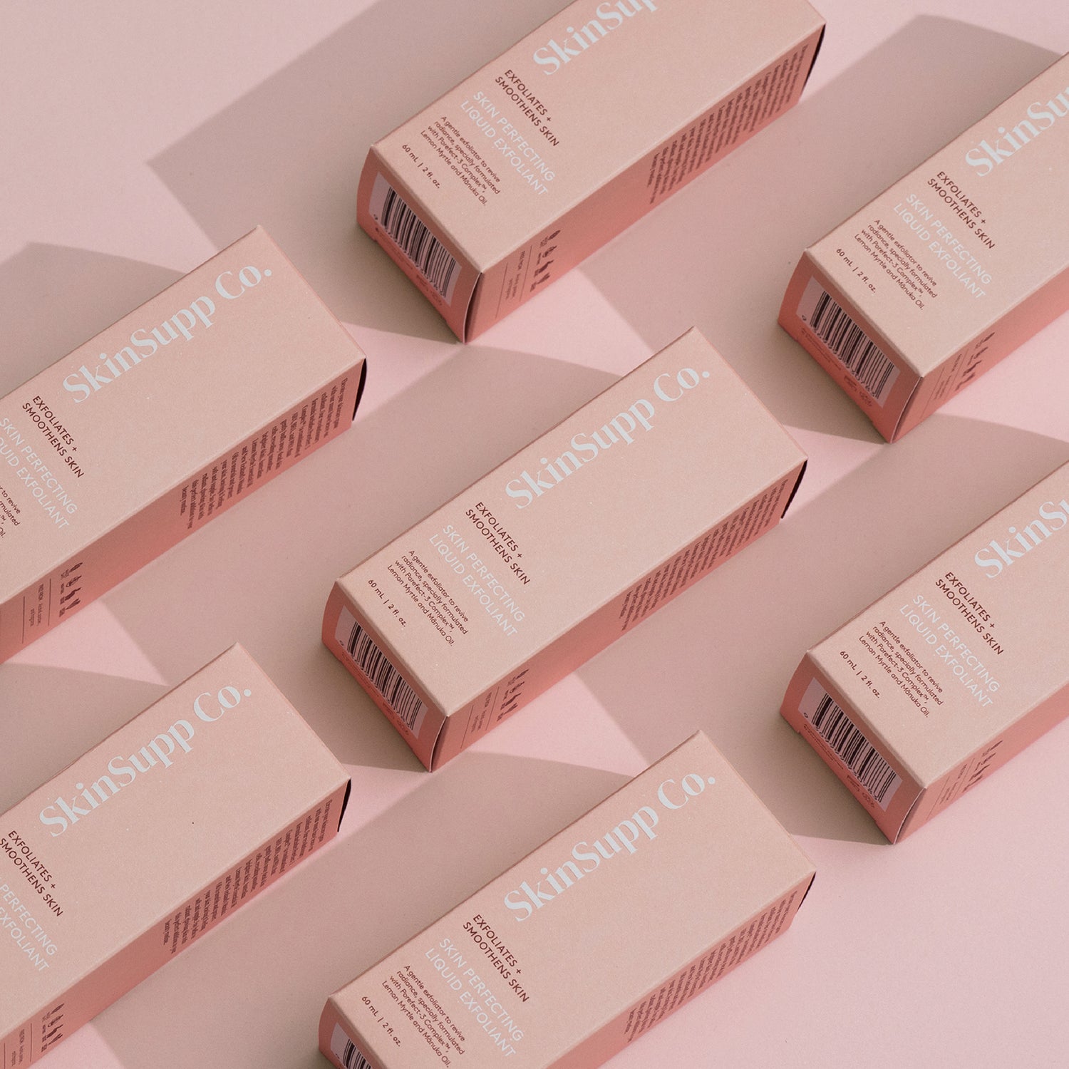 Collection of skincare items packaged in boxes on a pink tabletop